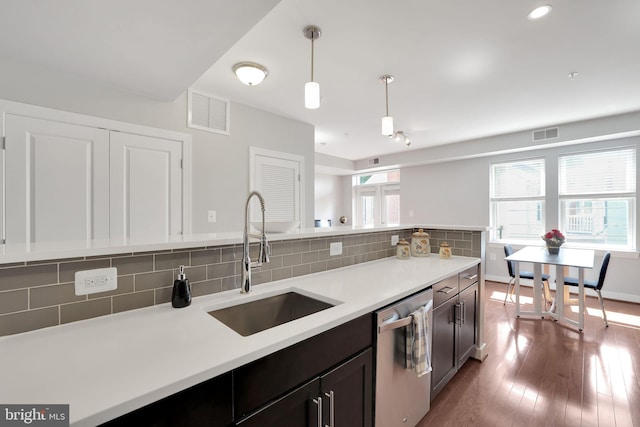 kitchen with decorative light fixtures, stainless steel dishwasher, decorative backsplash, and hardwood / wood-style flooring