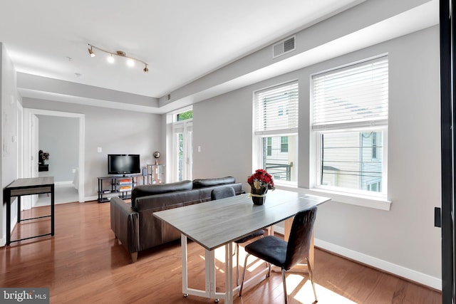 dining room with hardwood / wood-style flooring and track lighting