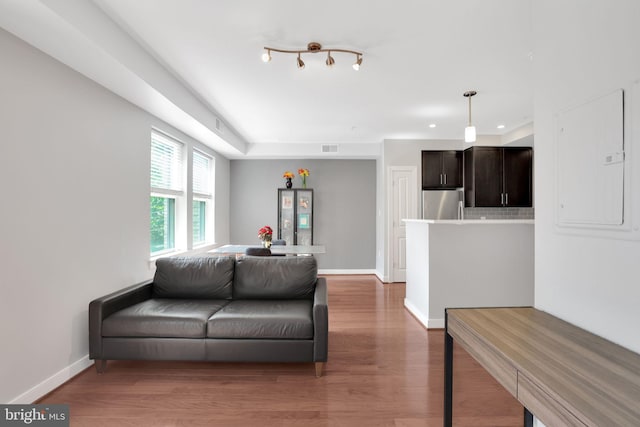 living room with rail lighting, hardwood / wood-style floors, and electric panel