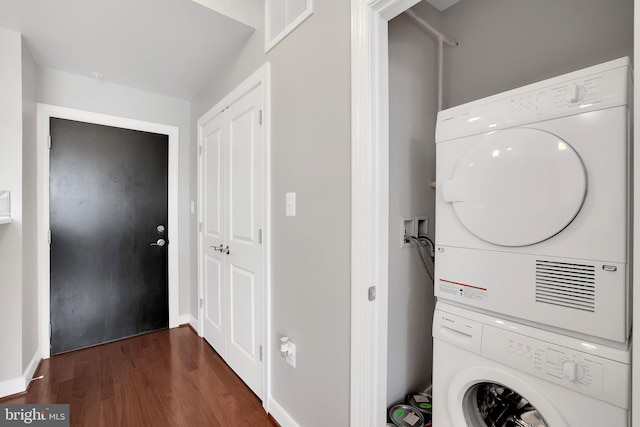 washroom featuring stacked washer and clothes dryer and dark hardwood / wood-style flooring