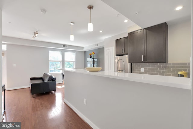 kitchen featuring tasteful backsplash, stainless steel fridge, hanging light fixtures, dark brown cabinetry, and dark hardwood / wood-style floors