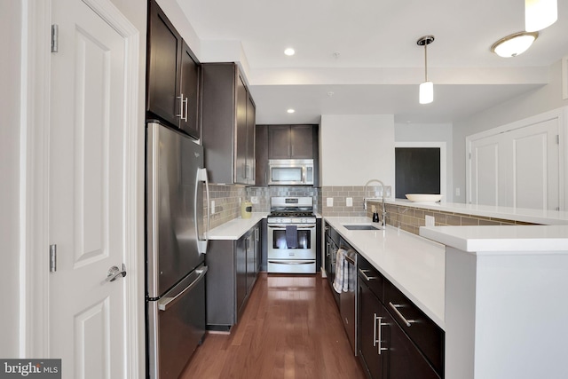 kitchen with decorative light fixtures, sink, appliances with stainless steel finishes, backsplash, and dark wood-type flooring