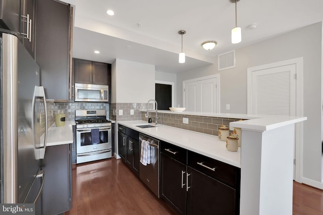 kitchen featuring tasteful backsplash, stainless steel appliances, dark hardwood / wood-style flooring, pendant lighting, and sink