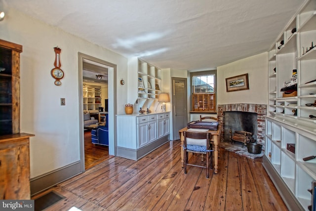 sitting room featuring wood-type flooring and a brick fireplace