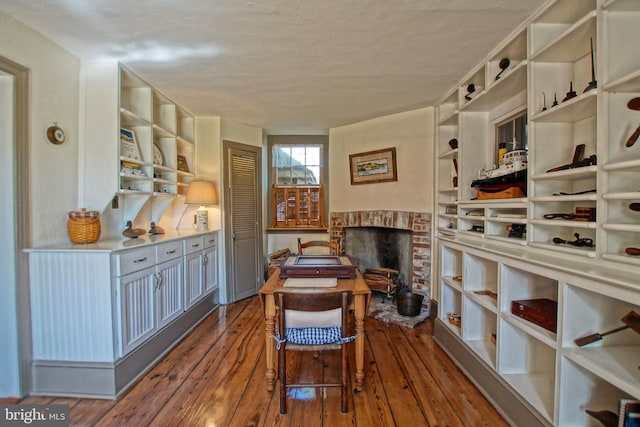 wine room featuring wood-type flooring, a fireplace, and a textured ceiling