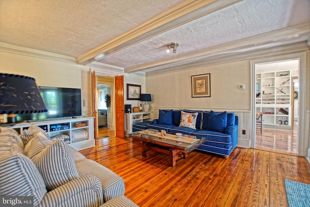 living room featuring hardwood / wood-style floors, beamed ceiling, ornamental molding, a textured ceiling, and built in shelves