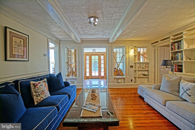 living room featuring crown molding, wood-type flooring, a textured ceiling, and built in shelves