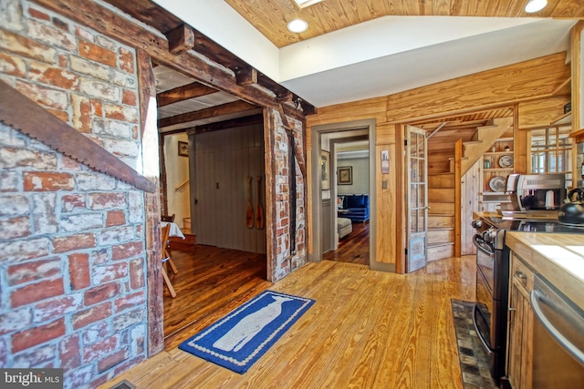 kitchen featuring wooden ceiling, appliances with stainless steel finishes, hardwood / wood-style floors, and wood walls