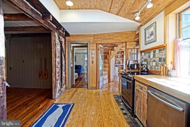 kitchen featuring wood ceiling, hardwood / wood-style flooring, appliances with stainless steel finishes, tile counters, and wood walls