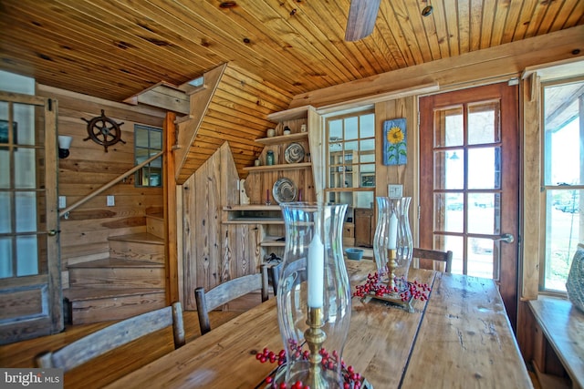 unfurnished dining area with wood ceiling, hardwood / wood-style flooring, wooden walls, and ceiling fan