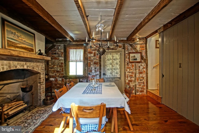 dining area featuring hardwood / wood-style floors, beamed ceiling, wooden walls, and a brick fireplace