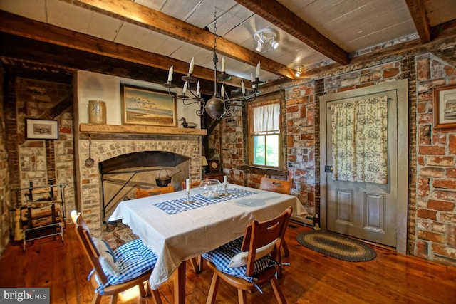 dining area with brick wall, hardwood / wood-style floors, a brick fireplace, wooden ceiling, and beam ceiling