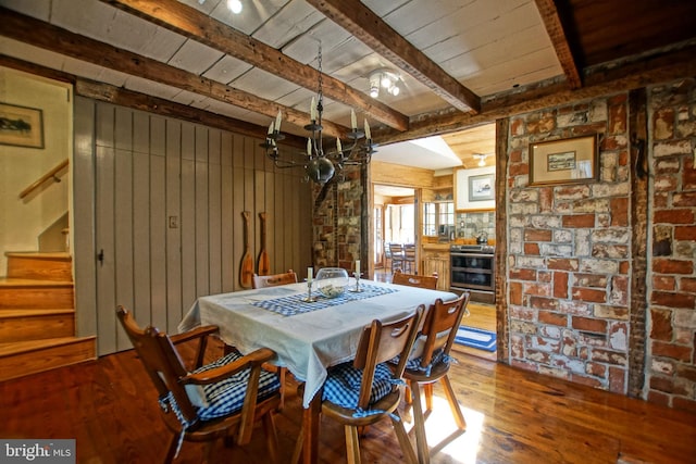 dining area with hardwood / wood-style flooring, wooden walls, wood ceiling, and beam ceiling