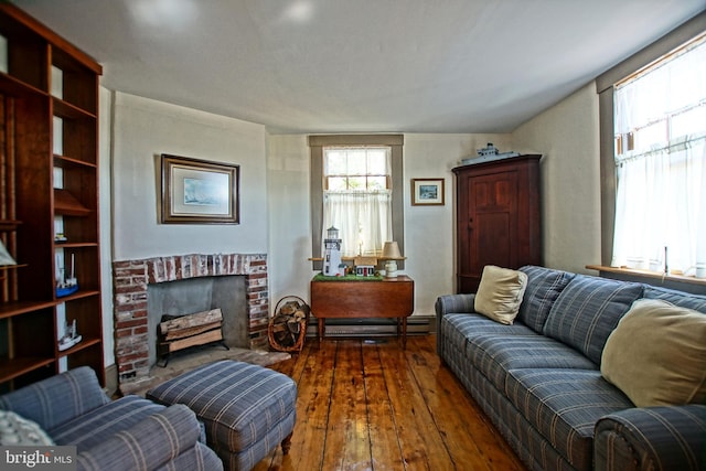 living room featuring baseboard heating, dark hardwood / wood-style floors, and a brick fireplace