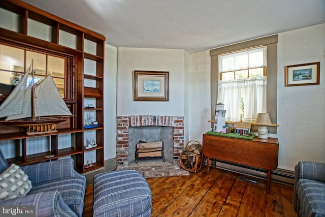 sitting room with dark hardwood / wood-style flooring, a brick fireplace, and a baseboard radiator