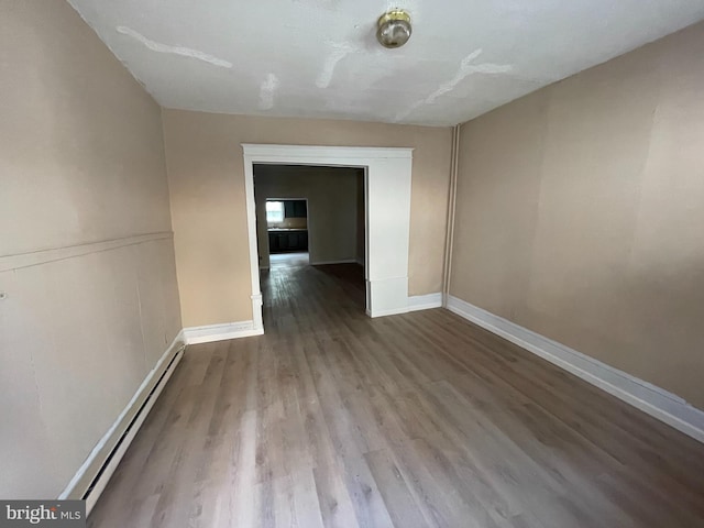 spare room with a baseboard heating unit and wood-type flooring