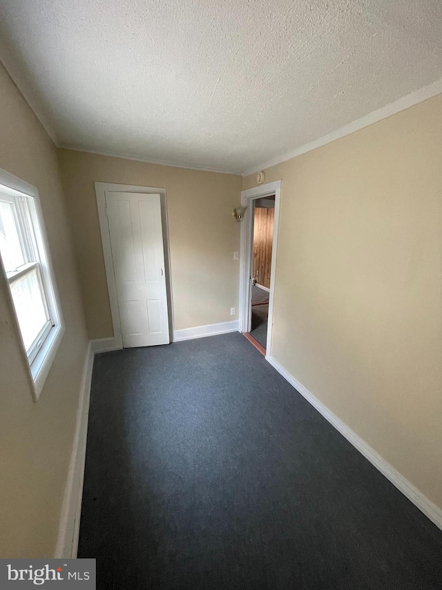 unfurnished bedroom featuring a closet, dark carpet, and a textured ceiling