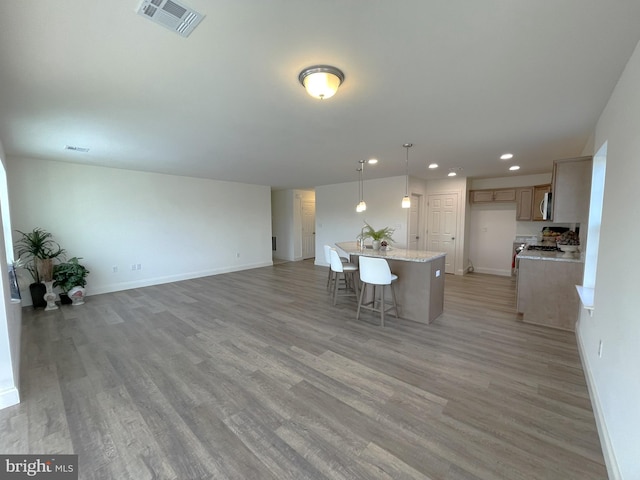 kitchen with light stone countertops, a kitchen island, hardwood / wood-style flooring, and decorative light fixtures