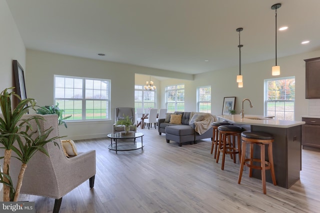 living room with light hardwood / wood-style floors, sink, and a notable chandelier