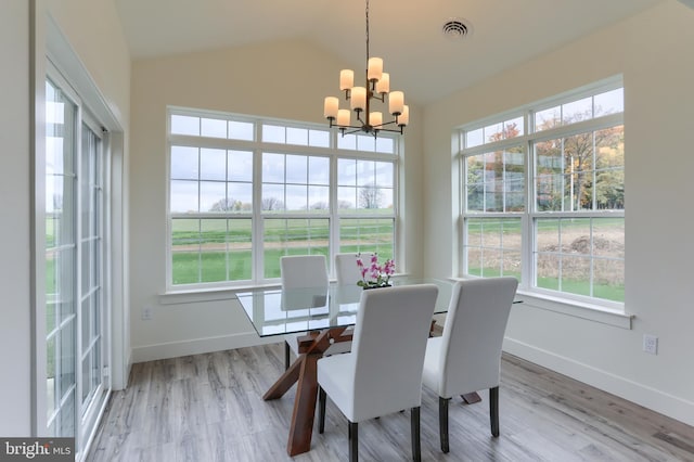 dining area with vaulted ceiling, light hardwood / wood-style flooring, and a notable chandelier