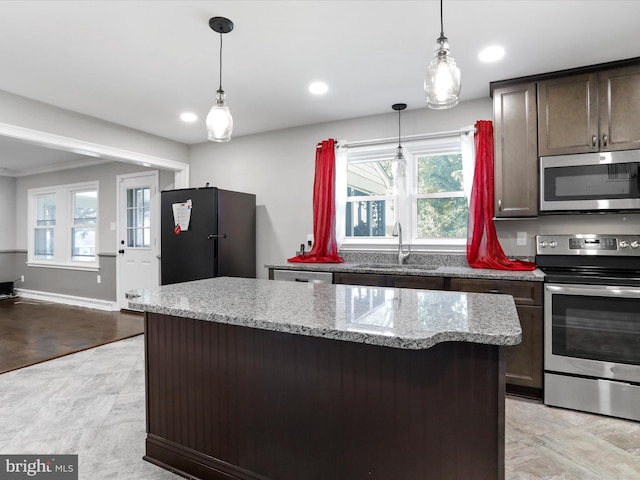 kitchen featuring sink, light stone counters, a center island, dark brown cabinets, and appliances with stainless steel finishes