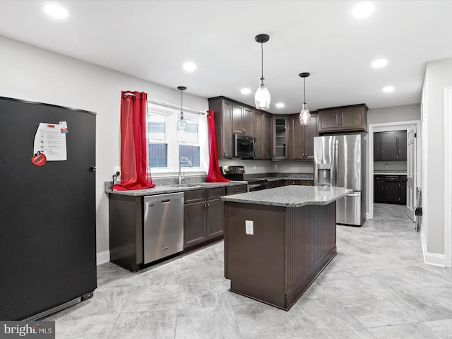 kitchen featuring dark brown cabinetry, hanging light fixtures, dark stone countertops, appliances with stainless steel finishes, and a kitchen island