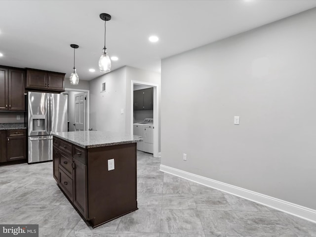 kitchen with stainless steel refrigerator with ice dispenser, dark brown cabinetry, light stone counters, a center island, and hanging light fixtures