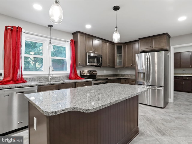 kitchen featuring a kitchen island, decorative light fixtures, sink, dark brown cabinetry, and stainless steel appliances