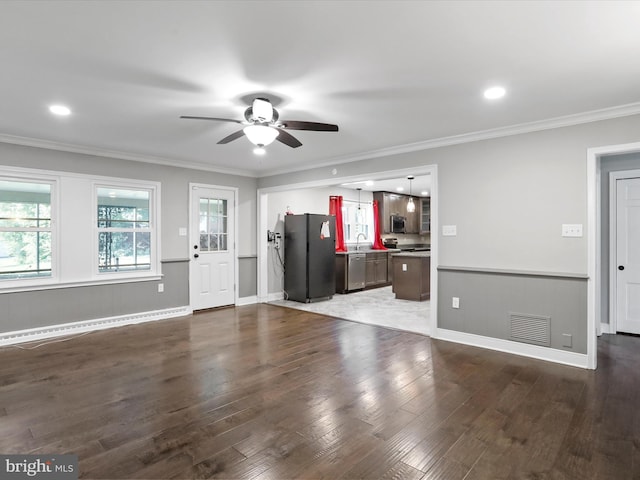 unfurnished living room with crown molding, a baseboard heating unit, ceiling fan, and dark hardwood / wood-style flooring