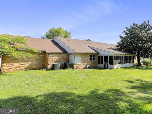 back of property featuring a sunroom, central air condition unit, and a lawn