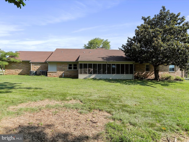 rear view of property featuring central AC, a sunroom, and a lawn