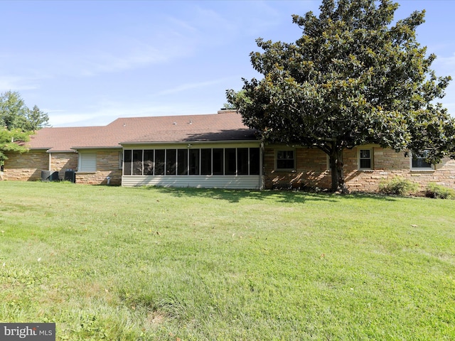 rear view of house featuring a sunroom and a lawn