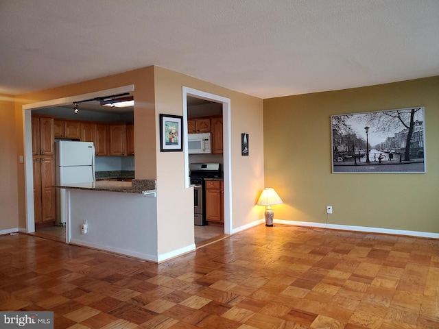 kitchen featuring light parquet flooring, white appliances, and a textured ceiling