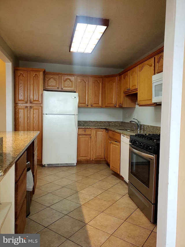 kitchen with stone countertops, sink, white appliances, and light tile patterned floors