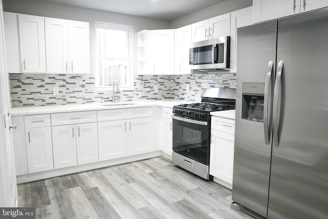 kitchen featuring appliances with stainless steel finishes, light hardwood / wood-style flooring, white cabinetry, and sink