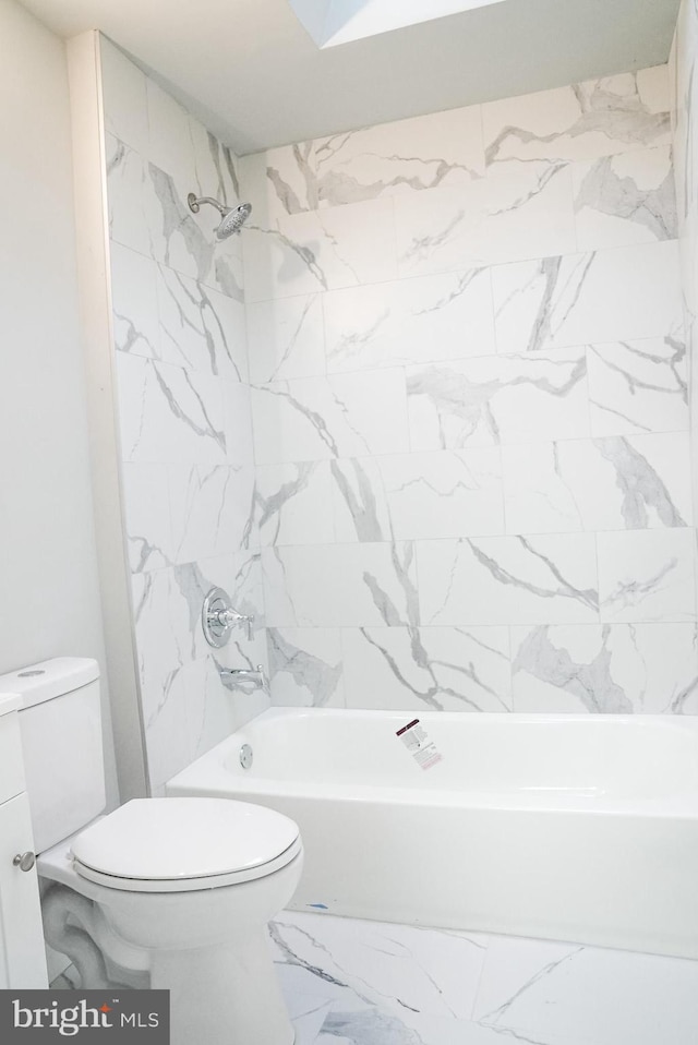 bathroom featuring tile patterned flooring, toilet, and tiled shower / bath combo