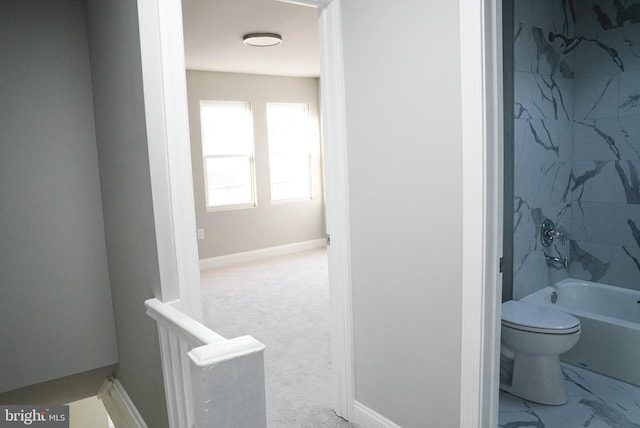 bathroom featuring tiled shower / bath combo and toilet