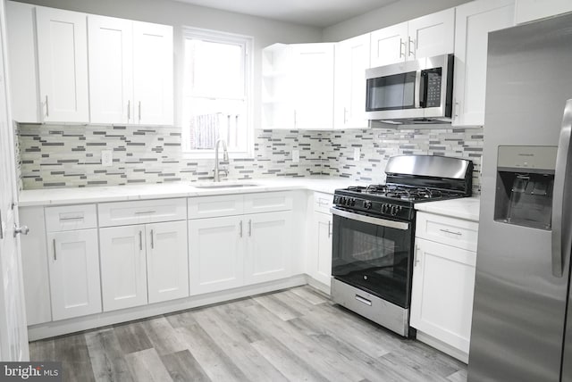 kitchen with white cabinetry, light hardwood / wood-style flooring, backsplash, stainless steel appliances, and sink