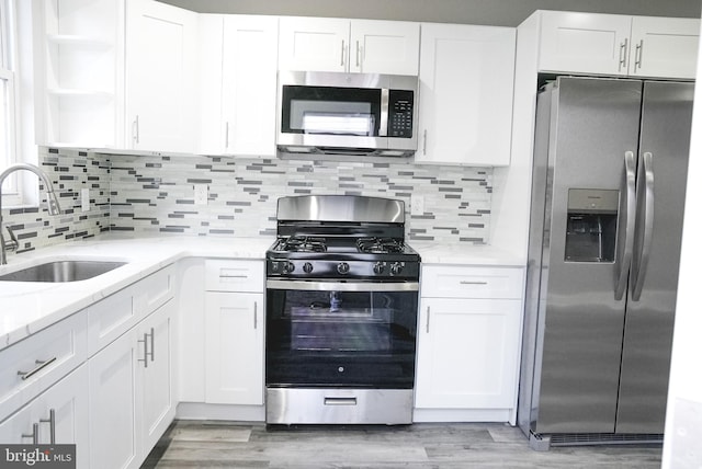 kitchen featuring light stone counters, stainless steel appliances, light hardwood / wood-style floors, decorative backsplash, and sink