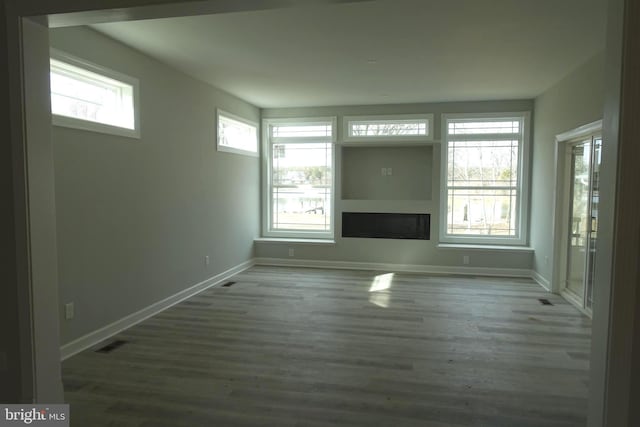 unfurnished living room with visible vents, baseboards, wood finished floors, and a fireplace