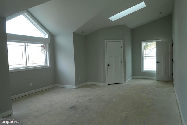 unfurnished room featuring baseboards and lofted ceiling with skylight