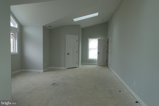 spare room featuring baseboards and lofted ceiling with skylight