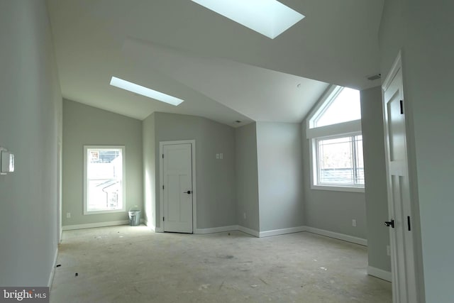 additional living space with vaulted ceiling with skylight and baseboards