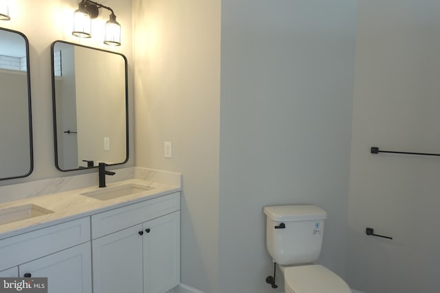 bathroom with double vanity, toilet, and a sink