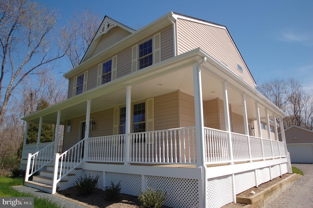 farmhouse-style home with a garage, an outbuilding, and a porch