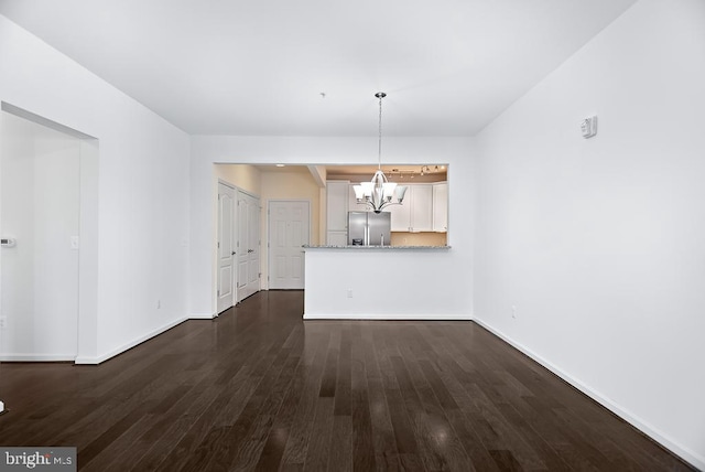 unfurnished dining area featuring a chandelier and dark wood-type flooring