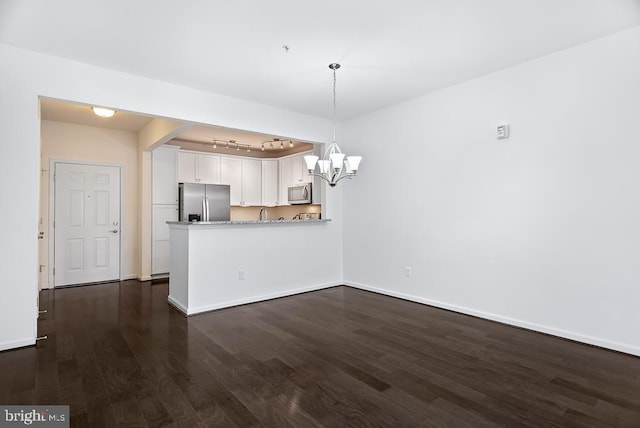 kitchen featuring appliances with stainless steel finishes, kitchen peninsula, white cabinets, and dark wood-type flooring