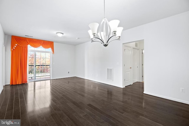 empty room with dark hardwood / wood-style flooring and an inviting chandelier