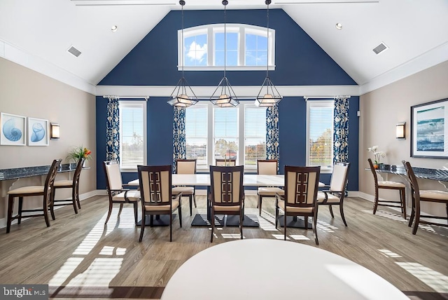 dining room with a notable chandelier, high vaulted ceiling, and wood-type flooring