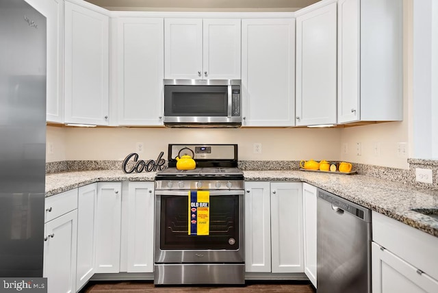 kitchen with light stone countertops, appliances with stainless steel finishes, and white cabinets